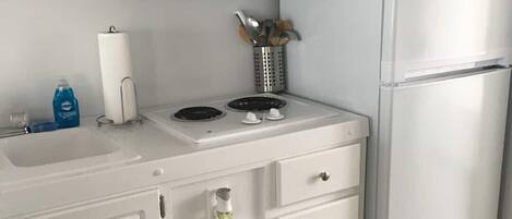 Une cuisine avec des meubles blancs, un four à micro-ondes, une cuisinière et un réfrigérateur.