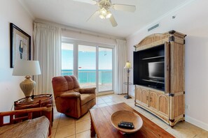 Relax in this stylish living room with a sofa, coffee table, and TV, offering a view of the sea through large glass doors.