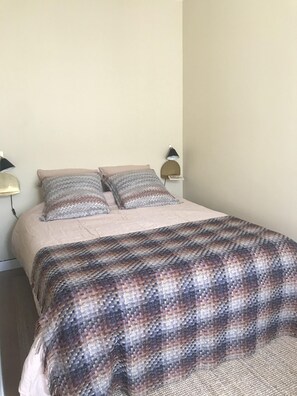 Un lit bien fait, avec une couverture à motifs, deux oreillers et deux lampes de chevet.