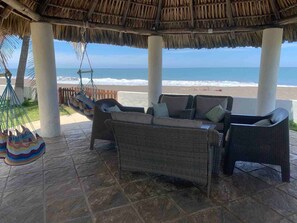 A beachside patio with wicker furniture and a hammock, overlooking the ocean. - Beach House in Monterrico - Directly on the beach  (Monterrico)