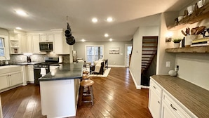 A spacious kitchen with a central island, wooden flooring, and white cabinetry.