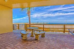 Enjoy a tranquil beachside retreat with a patio featuring a stone table and a wooden fence.