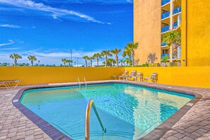 Relax by the pool surrounded by palm trees and lounge chairs.