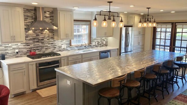 A modern kitchen with a large island, stainless steel appliances, and a unique backsplash.