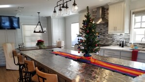A modern kitchen with a large island, bar stools, a Christmas tree, and a decorative ribbon.