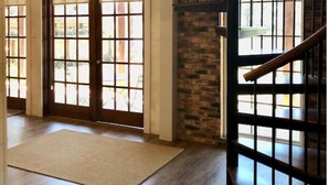 A spacious room with a wooden floor, a large window, and a staircase with a metal railing.