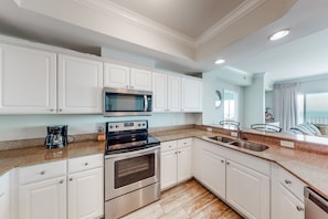Enjoy cooking in this kitchen with sleek cabinetry, stainless steel appliances, and a granite countertop, featuring a double oven, microwave, and coffee maker.