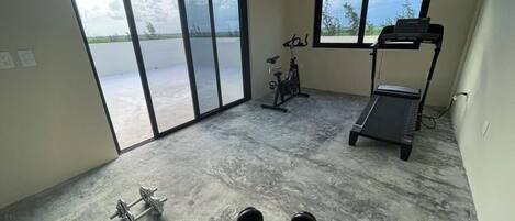 A gym with a treadmill, exercise bike, and dumbbells.