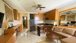 A modern living room with a sofa, coffee table, and a TV on a wooden cabinet. - GAIA ~ One Bedroom Condo w/Pool. New Build✨ (Puerto Morelos)