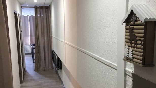 Ein schmaler Flur mit einer hölzernen Sitzbank, einem Heizkörper und einer dekorativen Wandverkleidung.