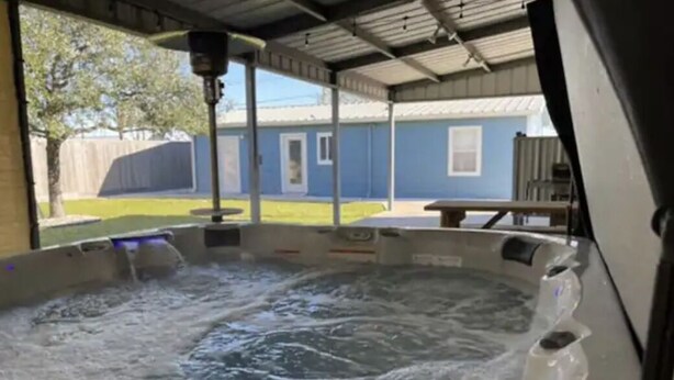 A hot tub with a metal roof and a view of a backyard with a fence and a house.