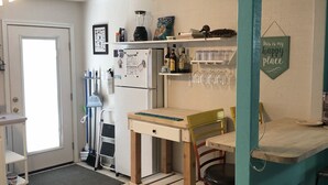 A kitchen with a teal accent wall, a wooden table, a refrigerator, and a hanging sign that says "This is my happy place".