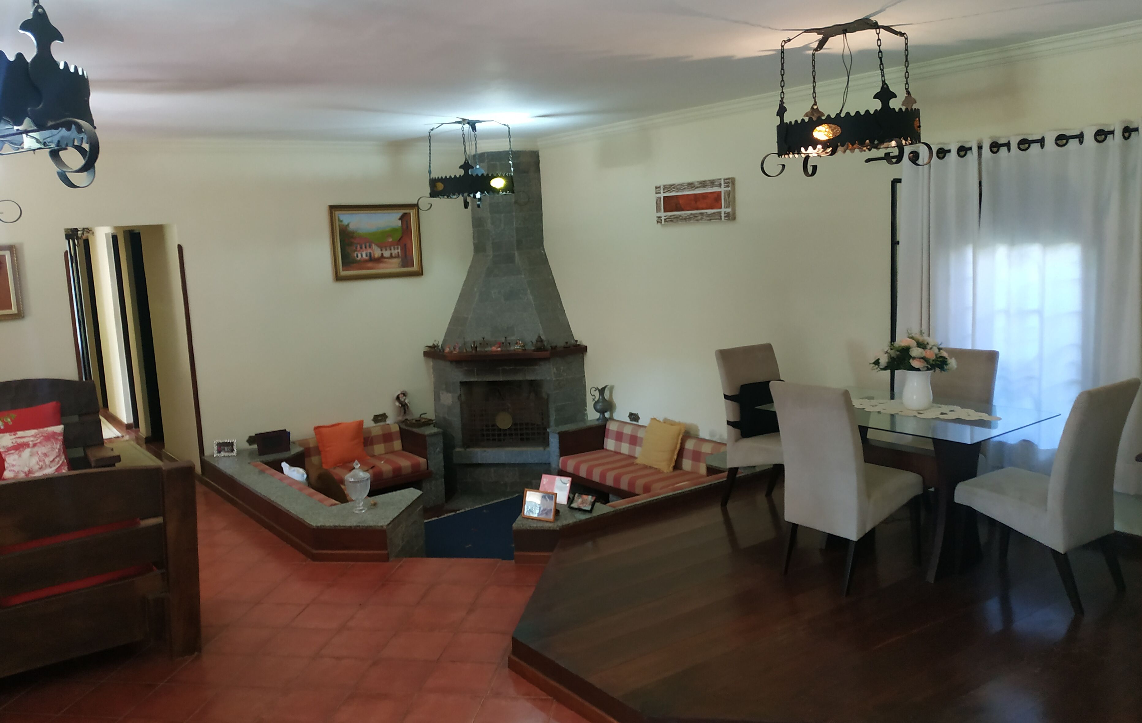 A living room with a fireplace, a dining area with a glass table, and a sofa set.