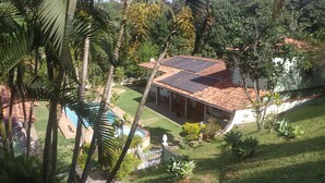 Una casa con techo de paneles solares, rodeada de exuberante vegetación y una piscina.