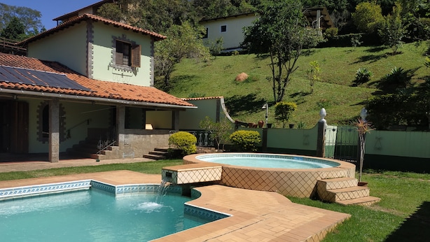 Propiedad residencial con piscina, jacuzzi y una escalera que conduce a un patio cubierto.