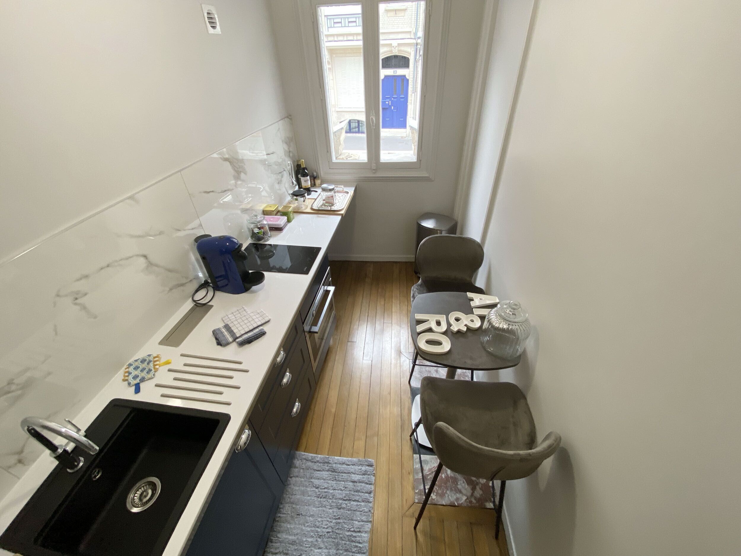 A compact kitchen with a sink, a coffee machine, and a small dining area with a table and chairs.