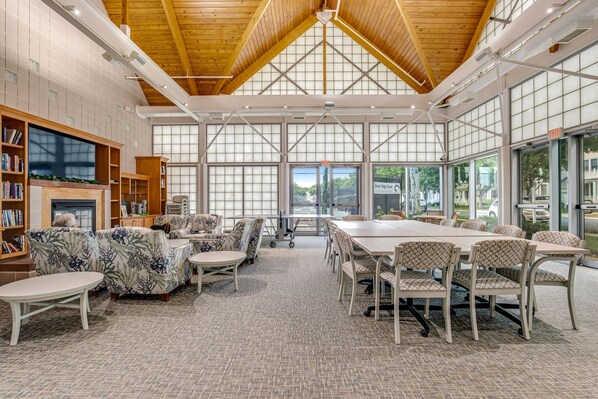 Meetings take place in this well-appointed room with a high ceiling, long table, and comfortable seating.