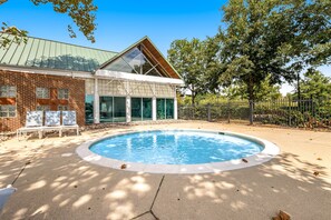 Relax by the pool surrounded by a serene garden with mature trees and lounge chairs.