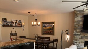 A modern living room with a white sofa, a dining area with a wooden table and chairs, a stone fireplace, and artwork on the walls. - Beautiful Vail Mountain View Condo with Shuttle to Skiing - sleeps 6! Simba Run (Vail)