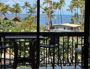Un balcone con vista sull'oceano e palme.