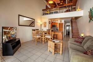 Relax in this inviting living area with a sofa, dining table, and mounted TV.