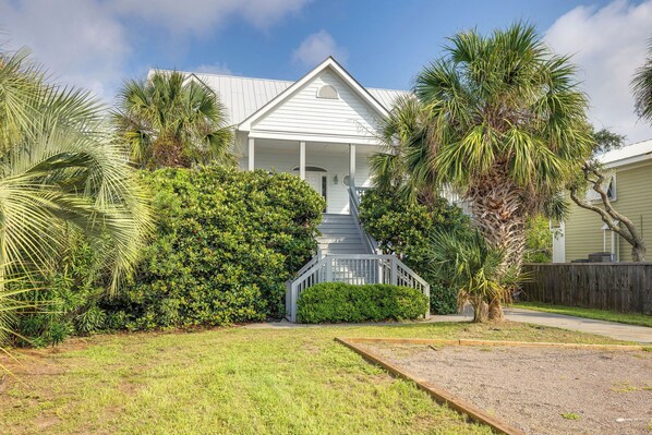 A residential house with a front porch, a staircase leading to the entrance, and a well-maintained lawn.