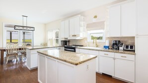 Een moderne keuken met witte kasten, granieten aanrechtbladen en een centraal eiland.