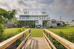 A two-story house with a wooden deck leading to a covered outdoor area.