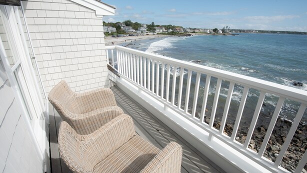 A balcony with wicker chairs overlooking a beach and ocean. - Spectacular 4-Bedroom Luxury Home with Ocean and Mother's Beach Views! (Kennebunk)