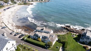 A coastal property with a large house, a driveway, and a beach view. - Spectacular 4-Bedroom Luxury Home with Ocean and Mother's Beach Views! (Kennebunk)