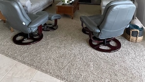 A living room with a ceiling fan, a sofa, two armchairs, a coffee table, and a television. - Lake Front Condo - You’ll never want to leave! Central AC & air purifiers - (Polson)