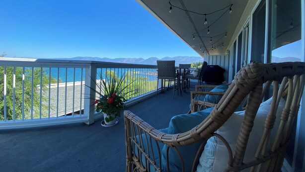 A balcony with wicker furniture, a grill, and a view of the sea. - Lake Front Condo - You’ll never want to leave! Central AC & air purifiers - (Polson)