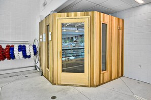Relax in a compact sauna with a glass door, adjacent to a unique glass bottle display.