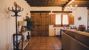 Un salón acogedor con techo de madera, un sofá, una mesa y una lámpara.