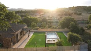 Una piscina con vistas a un paisaje rural, rodeada por una valla de madera y un edificio de piedra.
