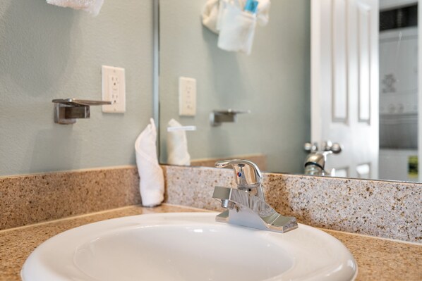 A bathroom sink with a modern faucet, a mirror, and a towel rack.