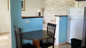Eine kleine Küche mit Esstisch und Stühlen, einem Kühlschrank und einem Deckenventilator.