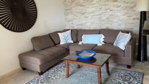 Ein Wohnzimmer mit einer Eckcouch, einem Couchtisch und einem gemusterten Teppich.