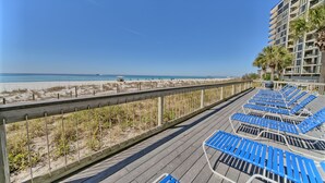 Un paseo marítimo con sillas reclinables azules y un muelle de madera.