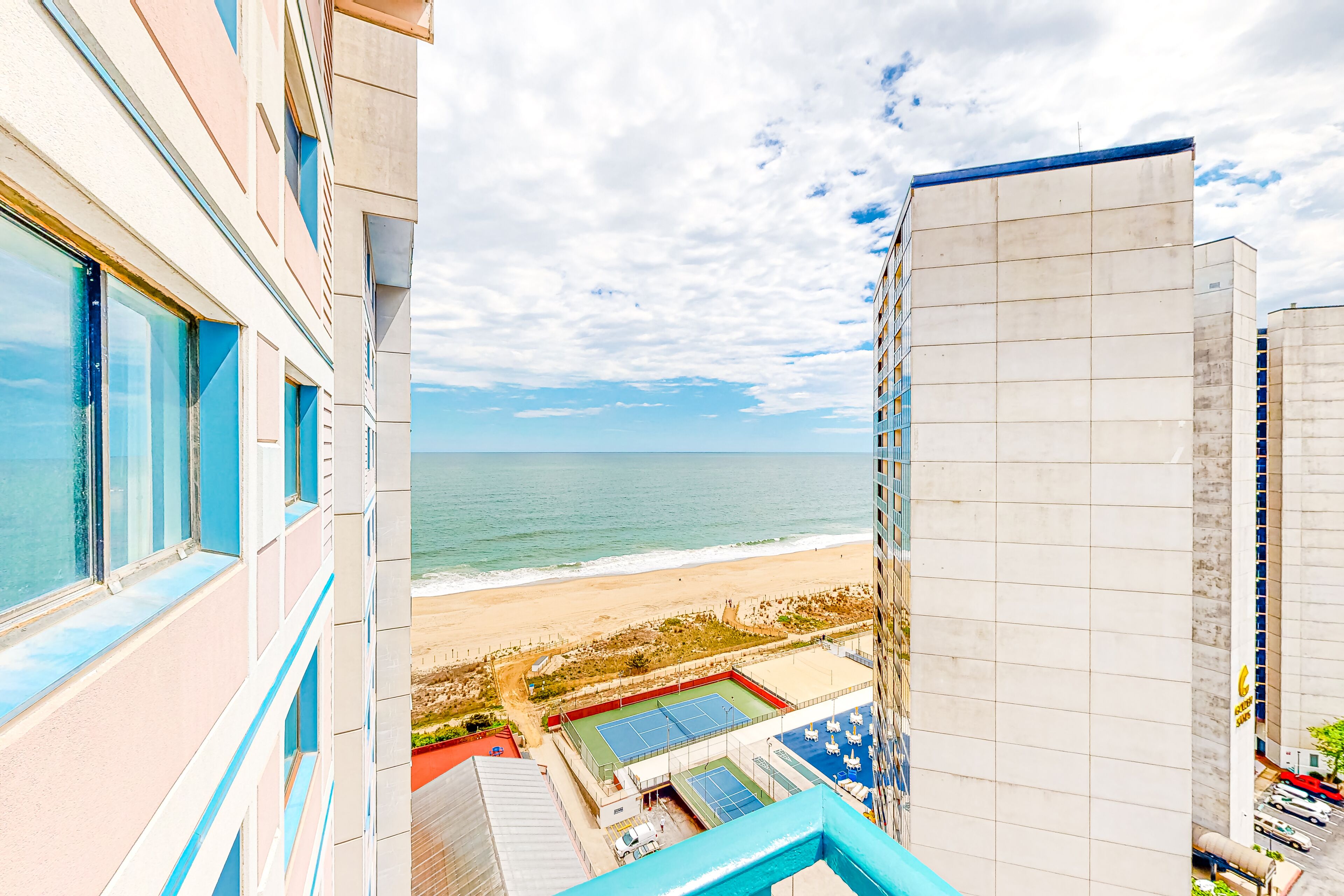 Bright coastal condo with pool access, side views of the ocean, balcony & W/D