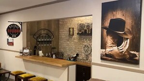 A bar area with stools, a wooden counter, and a wall-mounted sign. - StockYards!  Walk 3 Blocks-Ranch House sleeps 8, TCU close by (Ft Worth)