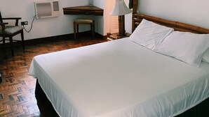 Un dormitorio con cama, escritorio, silla, ventana y ventilador de techo.