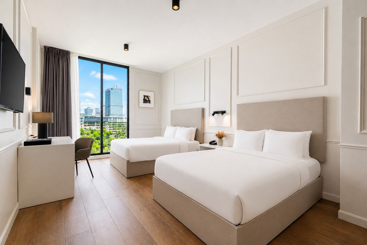 Habitación de hotel con dos camas, un escritorio, una silla, un televisor y un ventanal con vistas a la ciudad.
