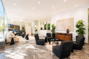 Een moderne lobby met zitplaatsen, een receptiebalie en een groot abstract schilderij.