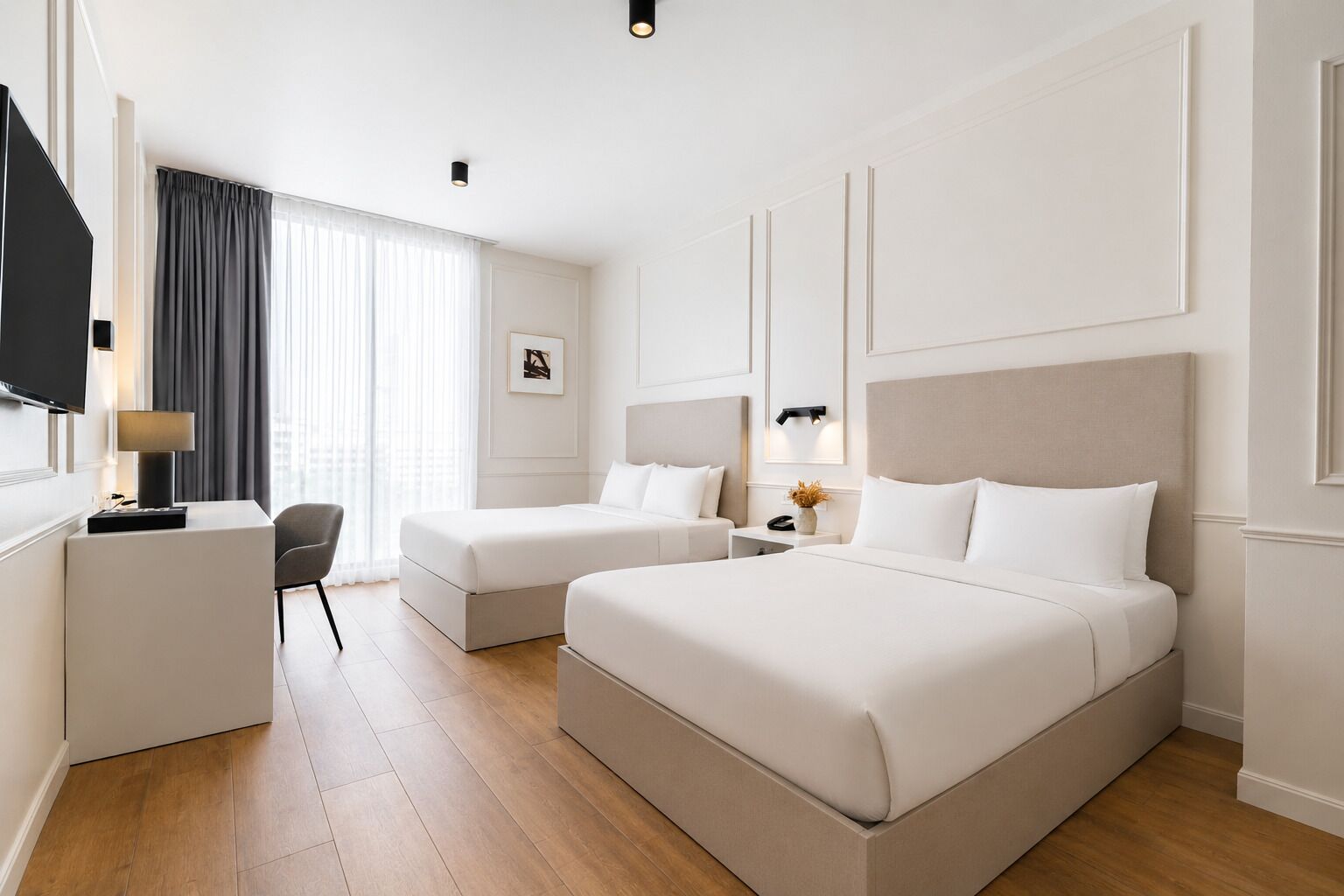 Ett hotellrum med två sängar, ett skrivbord, en stol, en TV och ett fönster med gardiner.