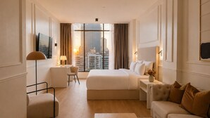 Habitación de hotel con una cama grande, un escritorio, una silla, un sofá y vistas a la ciudad.