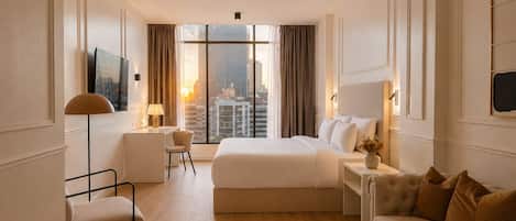 Une chambre d’hôtel avec un grand lit, un bureau, une chaise, un canapé et une vue sur le paysage urbain.