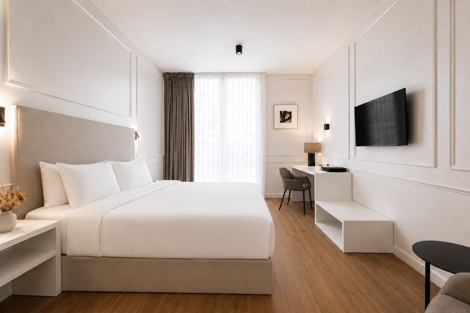 A hotel room with a large bed, a desk with a chair, a TV mounted on the wall, and a window with curtains.