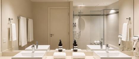 Un baño moderno con dos lavamanos, ducha y un espejo grande.