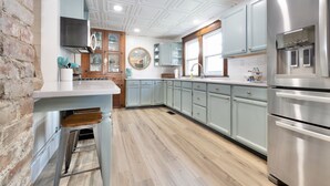 A kitchen with light blue cabinets, a stainless steel refrigerator, and a wooden island. - The Vintage Lake House w/ Private Dock (Russells Point)